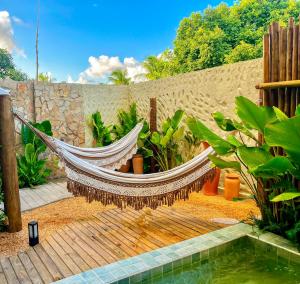 a hammock in a garden next to a fence at Villa Aconchego - Casas de Luxo in São Miguel dos Milagres