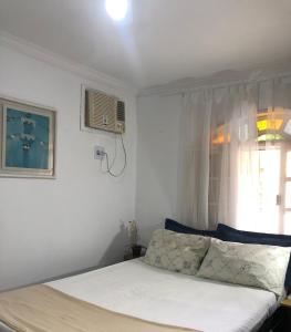 Schlafzimmer mit einem Bett und einem Fenster mit einem Ventilator in der Unterkunft Casa Bonita Rio das Ostras, ar condicionado, wifi, churrasqueira e garagem in Rio das Ostras