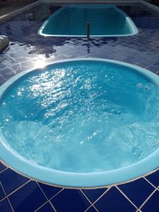 a large tub filled with blue water on a tile floor at Suites Inn Buzios da Dra in Búzios
