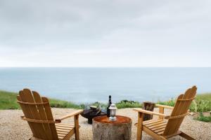 two chairs and a table with a bottle of wine at Off-grid Beachfront Cabin on Kangaroo Island in North Cape