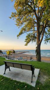 a park bench next to a tree and a beach at Dreamcatcher Coast House in Essex