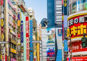 APA Hotel Higashi Shinjuku Kabukicho Tower في طوكيو: شارع المدينة مزدحم به العديد من الإشارات والمباني