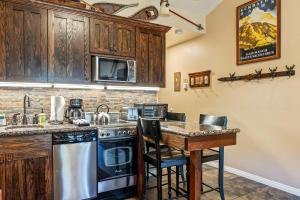 a kitchen with a stove and a counter with chairs at Cozy stay for 4, 5 Min Drive to Base, Full Kitchen, Shared Hot Tub & Pool, Restaurants Nearby! in Park City