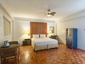 a bedroom with a bed and a table and a refrigerator at The Clipper Hotel Makati in Manila +44 photos