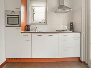 a kitchen with white cabinets and a sink at Bungalow by Water near Rotterdam in Simonshaven +22 photos