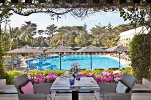 a patio with a table and chairs next to a pool at Palácio Estoril Hotel, Golf & Wellness in Estoril