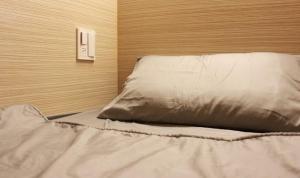 un letto con lenzuola e cuscini bianchi in una stanza di FC Hostel-Ruifang Station a Ruifang