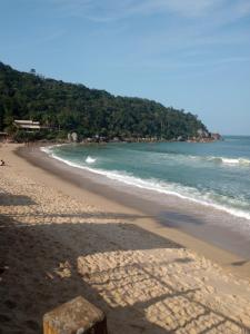 a sandy beach with the ocean and trees in the background at Hospedagem 4Lm in Penha