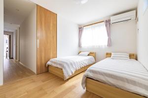 two beds in a room with white walls and wooden floors at 鎌倉-Reihome in Kamakura