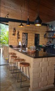 a kitchen with a counter and bar stools in it at Casa jardim com ofurô - Chapada dos veadeiros in Cavalcante