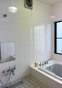 a white tiled bathroom with a tub and a window at I Love Izu in Futo +19 photos