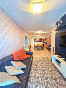 大普拉亚AP Elegante e luxuoso no Caiçara的客厅里有一张黑色皮沙发和一台电视