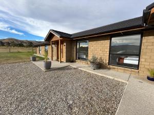 a house with a gravel driveway in front of it at Tarras Countryside Retreat - Near Tourist Route in Tarras