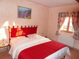 a bedroom with a large bed with a red blanket at Les Jardins de Bouteille in Manosque