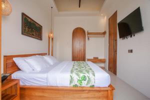 a bedroom with a white bed and a television at Thousand Sunday Ubud in Ubud