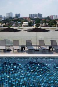 eine Gruppe von Stühlen und Sonnenschirmen neben einem Pool in der Unterkunft The StandardX, Bangkok Phra Arthit in Bangkok