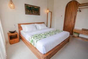 a bedroom with a large bed with a wooden frame at Thousand Sunday Ubud in Ubud