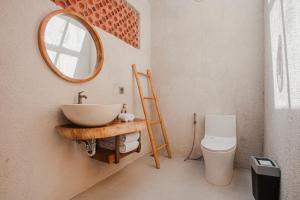 a bathroom with a sink and a mirror and a toilet at Thousand Sunday Ubud in Ubud