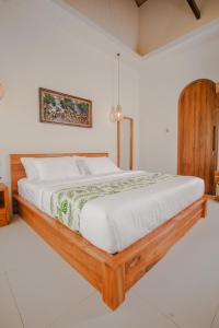 a bedroom with a large bed with a wooden frame at Thousand Sunday Ubud in Ubud