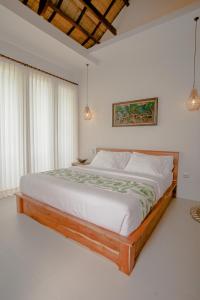 a bedroom with a large bed with white sheets at Thousand Sunday Ubud in Ubud