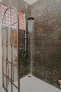 a shower in a bathroom with a brick wall at Thousand Sunday Ubud in Ubud