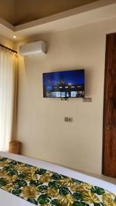 a bedroom with a bed with a television on the wall at Thousand Sunday Ubud in Ubud