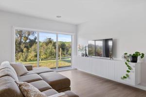 a living room with a couch and a large window at Centella House in Korumburra