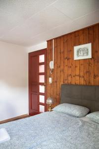 ein Schlafzimmer mit einem Bett und einer Holzwand in der Unterkunft Au Bord Du Lac in Därligen