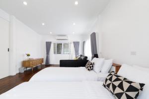 a white bedroom with two beds and a couch at Baan Boon in Bangkok