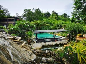a swimming pool in a garden with a waterfall at Keeree Loft Resort คีรีลอฟท์รีสอร์ท in Thong Pha Phum