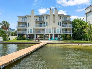 a large apartment building next to a body of water at Beautiful Roomy Condo with Sunrise & Sunset Views in St Pete Beach