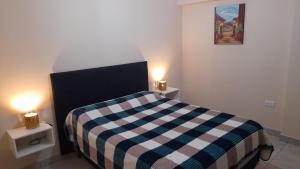 a bedroom with a bed with a checkered blanket and two lamps at Viento Zonda in Santa María