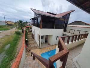 a house with a balcony with a swimming pool at Linda Casa Com Vista Pro Mar in Ilha Comprida