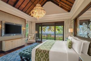 a bedroom with a bed and a television and a chandelier at The St. Regis Bali Resort in Nusa Dua