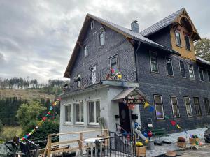 a large black house with a porch at Antique Hotel Am Bahndamm in Wallendorf