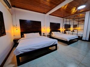 a bedroom with two beds and a mirror at Villa Wat San in Luang Prabang