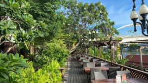 a row of tables and chairs with a bridge in the background at Krungsri River Hotel in Phra Nakhon Si Ayutthaya