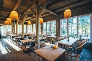a restaurant with wooden tables and chairs and windows at La Playa Resort & Camp Trzebinia in Trzebinia