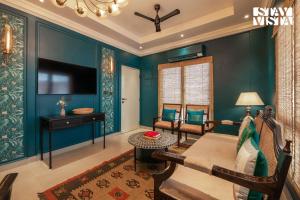 een woonkamer met blauwe muren en een bank en een tafel bij StayVista at Nayak House with Luxury Rooms, Terrace, Wi-Fi at Kolkata in Calcutta +14 foto's