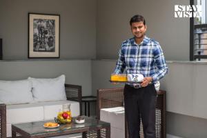 een man die een taart op een dienblad in een kamer vasthoudt bij StayVista at Nayak House with Luxury Rooms, Terrace, Wi-Fi at Kolkata in Calcutta