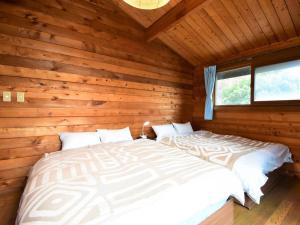 a bedroom with two beds in a log cabin at ヴィータ牛窓 in Setouchi