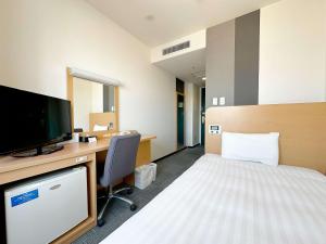 a hotel room with a bed and a desk with a television at Comfort Hotel Gifu in Gifu
