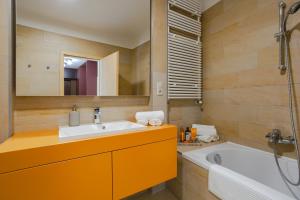 une salle de bain avec un lavabo, une baignoire et un miroir dans l'établissement Agora Apartman, à Pécs 14 autres photos