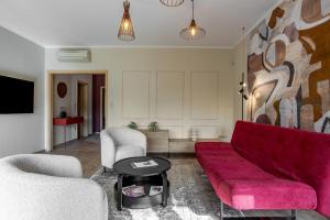 un salon avec un canapé rouge et deux chaises dans l'établissement Agora Apartman, à Pécs