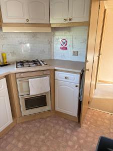 a kitchen with white cabinets and a stove top oven at 46 Newport Caravan Park Award Shortlisted Family Caravan in Hemsby +3 photos
