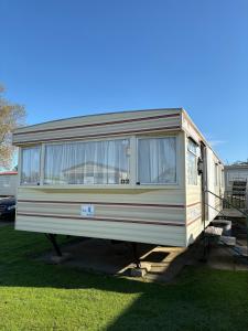 an rv parked in the grass in a yard at 46 Newport Caravan Park Award Shortlisted Family Caravan in Hemsby