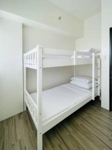 two white bunk beds in a room with wooden floors at WV 13 Family & Barkada Retreat in Iloilo City