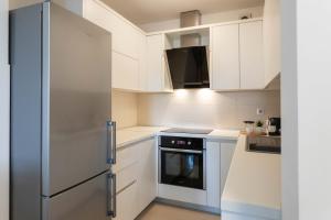 une cuisine avec des armoires blanches et un réfrigérateur en acier inoxydable dans l'établissement Bright 1BDR with Balcony & Parking, à Zagreb