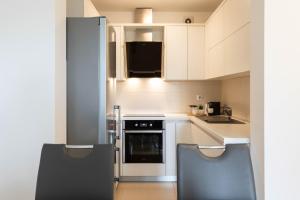 une cuisine avec des armoires blanches et un four noir dans l'établissement Bright 1BDR with Balcony & Parking, à Zagreb
