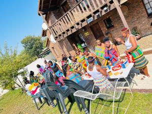 a group of people in colorful dresses sitting at a table at Duvha Guesthouse in Graskop